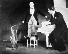 The musician clown Freddie jumps for joy on piano stool, partner P- Old Photo