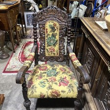 antique Jacobean-style carved oak armchair with a floral upholstered cushion Old