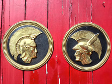 TWO VINTAGE DECORATIVE GOLD & BLACK METAL WALL PLAQUES ROMAN / GREEK SOLDIERS