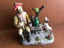 UNMARKED CAPODIMONTE STYLE FIGURINE OF A HUNTSMAN HAVING LUNCH WITH HIS DOG