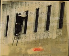 1986 Press Photo Worker Cleaning Row of Narrow Windows from Ladder - lrb38313