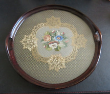 Antique round wooden tray with embroidered flowers and lace under glass