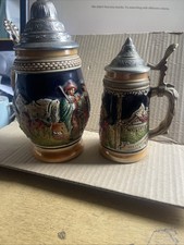 Two German Bier Steins 6 and 8 inch with lids.