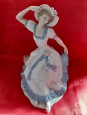 A Nao figure of a seated bonnetted lady